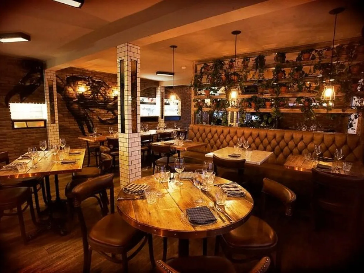 The warm and rustic interior of Kopar restaurant in Reykjavík's Old Harbour, featuring cozy leather seating and wood tables for the dinner cruise package.