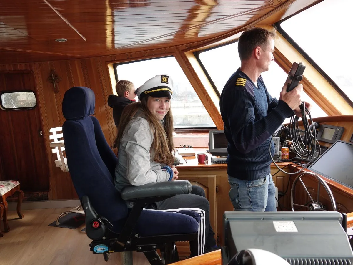 A child sitting in the captain's chair on the Amelia Rose yacht bridge during a family-friendly whale watching tour in Reykjavik.